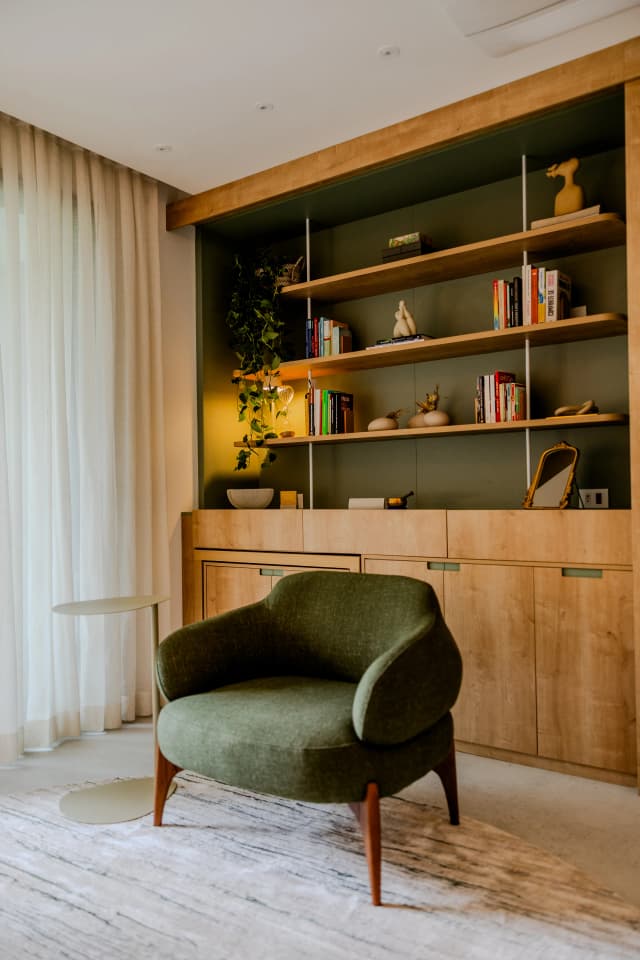 Poltrona verde confortável e estante com livros no espaço terapêutico